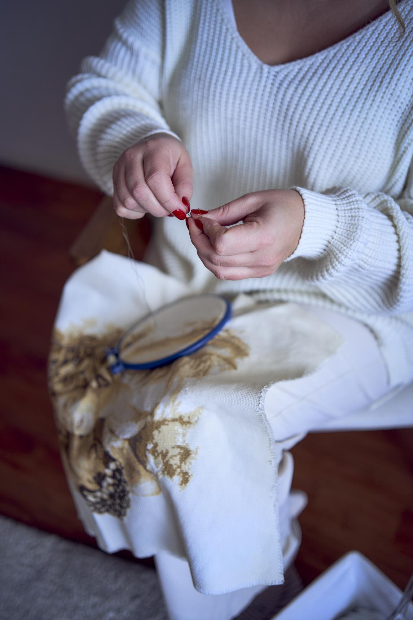 Hands embroidering a delicate pattern in studio